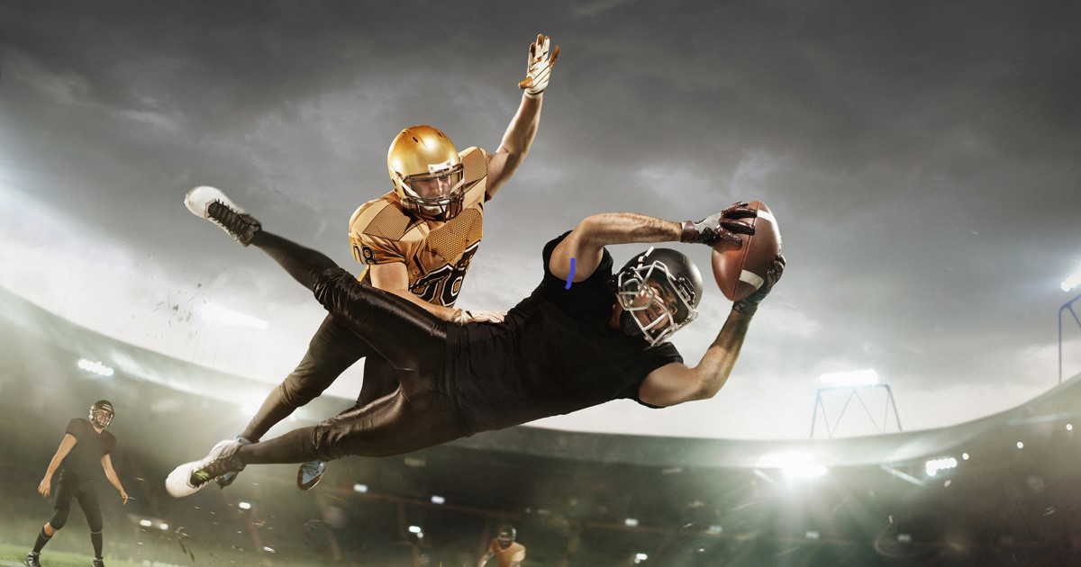 Wide receiver catching football while being defended