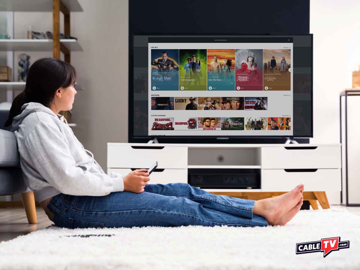 woman sitting on floor in front of a tv using the remote