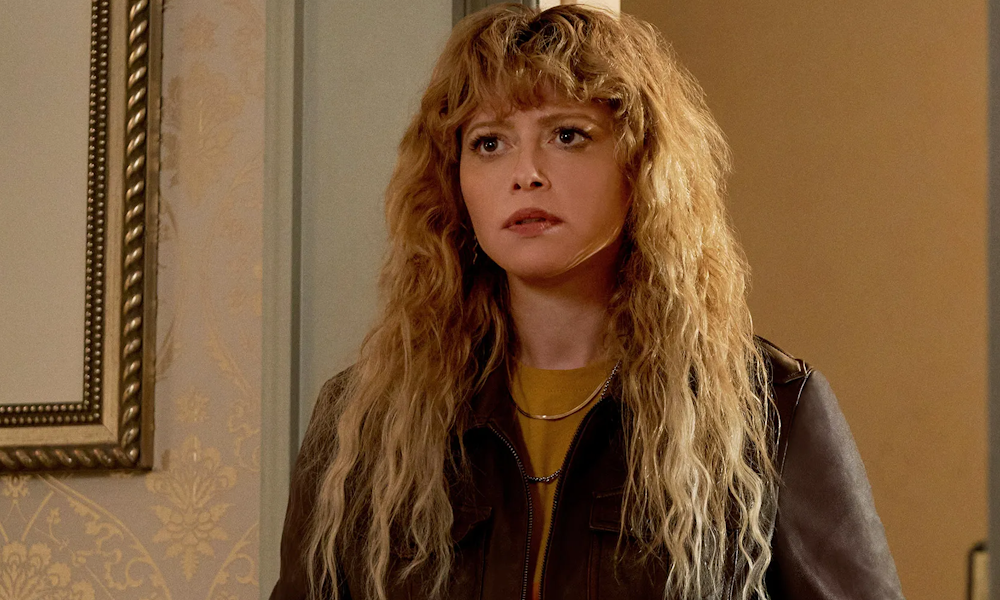 Natasha Lyonne, a woman with wavy red hair, from the show Poker Face.