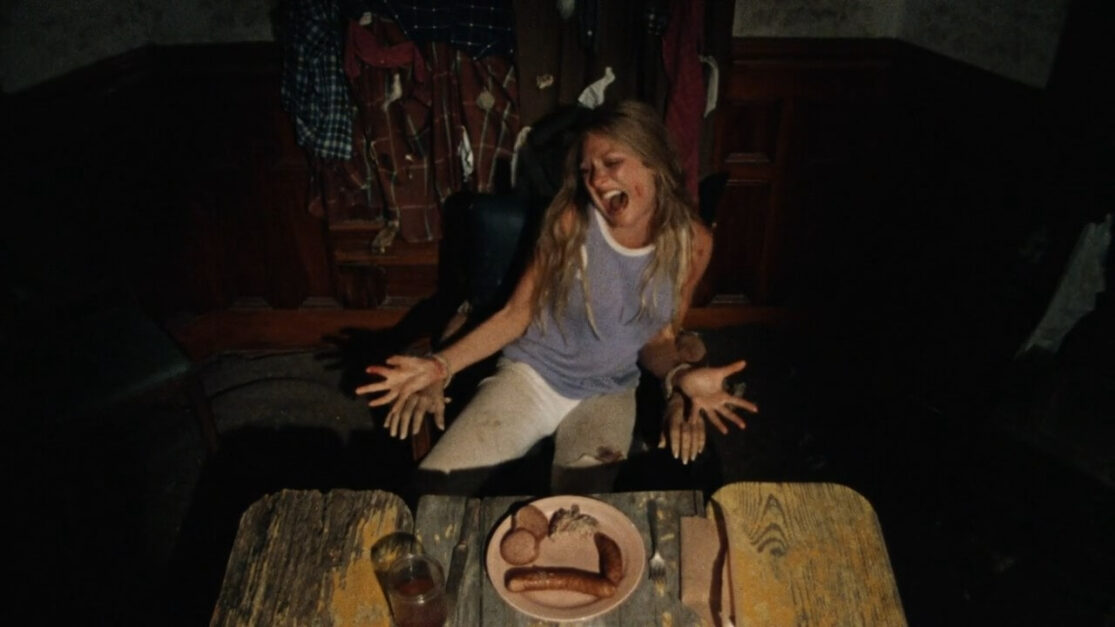 A screaming woman struggles to escape a chair made of human bones as a plate of mystery meat sits before her.