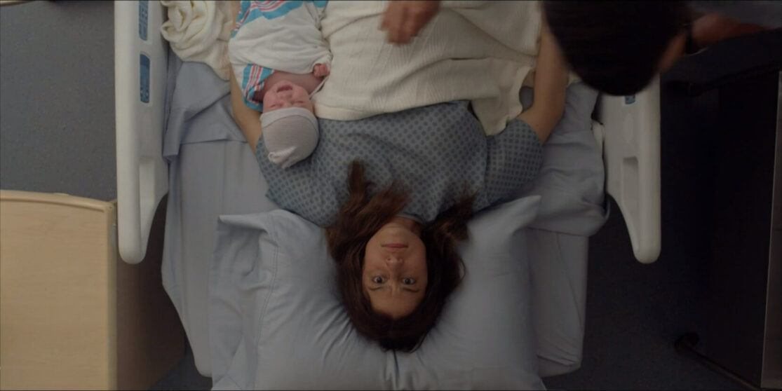 An upside-down shot of worried new mother lying with her newborn in the hospital.