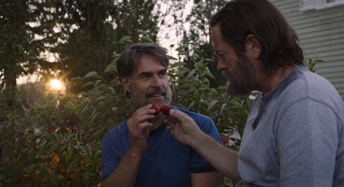 Nick Offerman and Murray Bartlett eating strawberries outside of a house in HBO's The Last of Us.