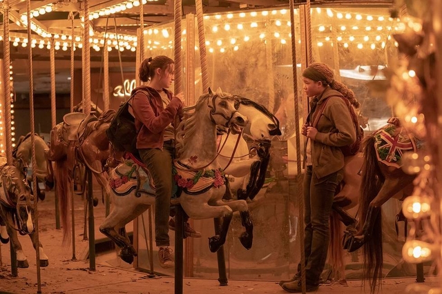 Bella Ramsey and Storm Reid sitting on a carousel in HBO's The Last of Us.