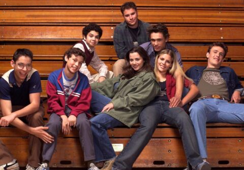 The cast of Freaks and Geeks sitting on bleachers.
