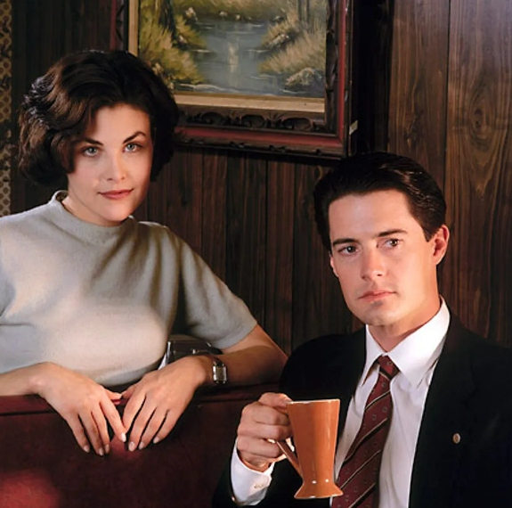 Young man holding a drink sitting with a young woman