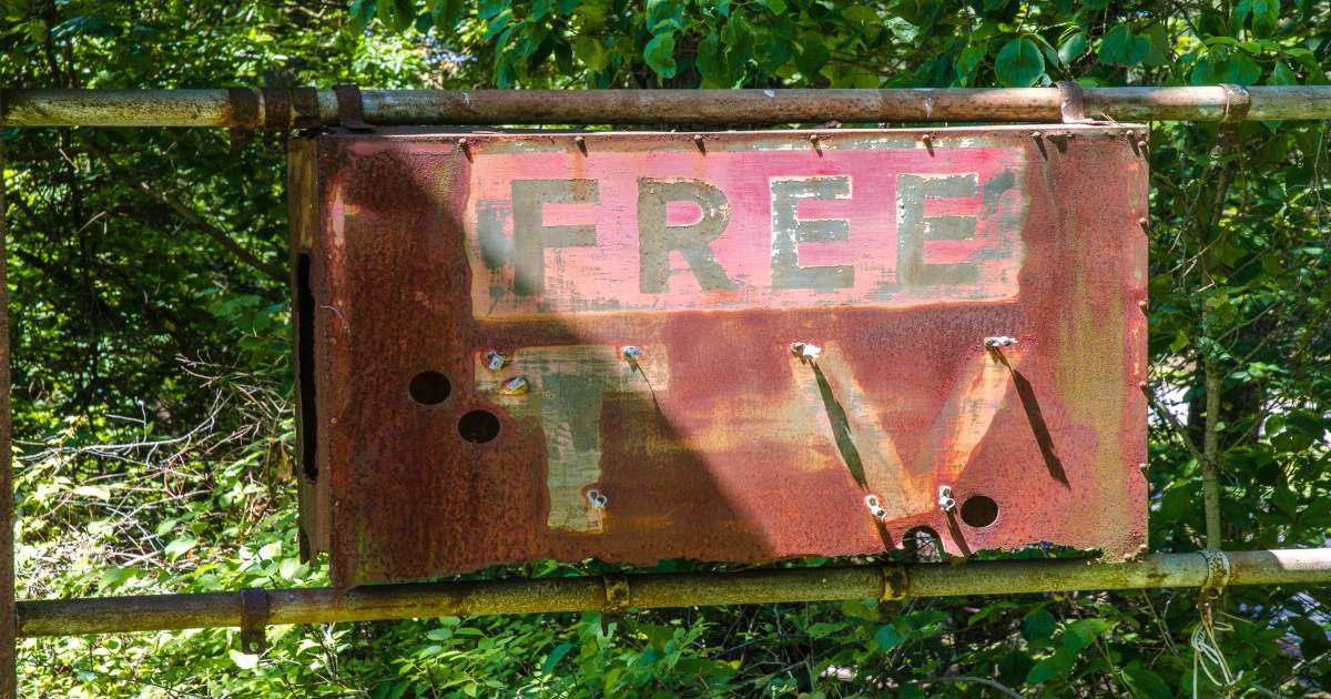 Among trees sits a rusty sign saying, FREE TV.