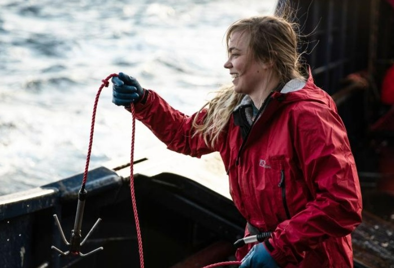Sara, a greenhorne on the Saga fishing boat, prepares to throw a hook into the Bering Sea..