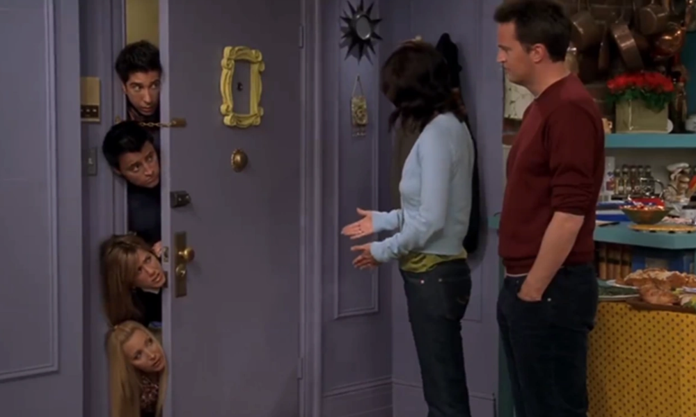 Four of the friends from Friends stick their heads around a door in a row.
