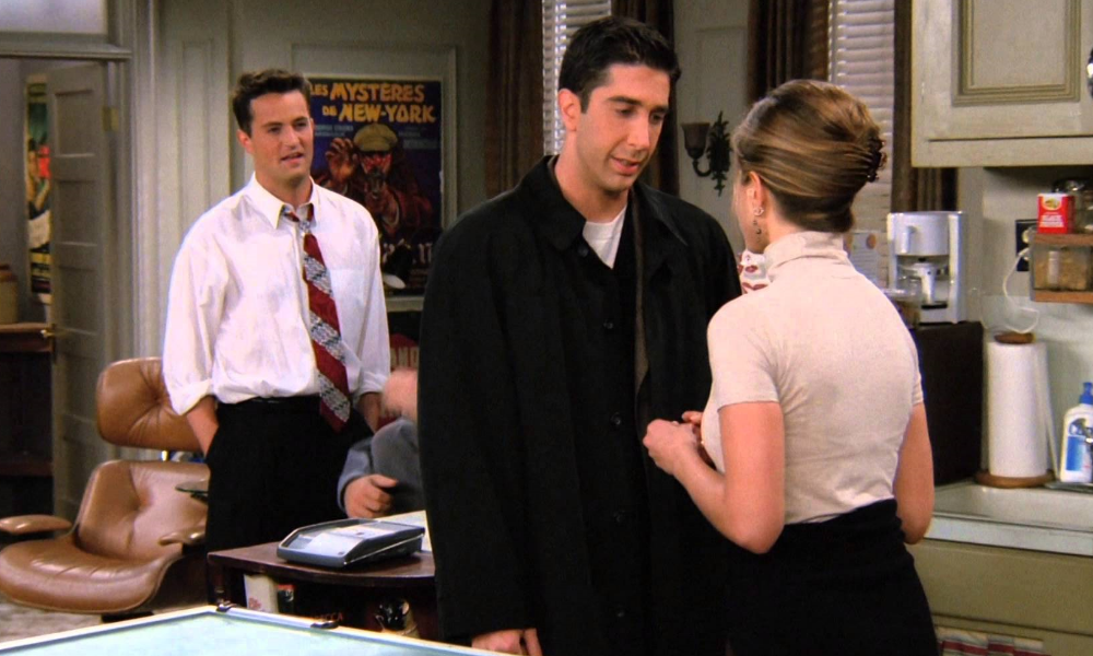 Rachel and Ross have a conversation while Chandler stands in the background.