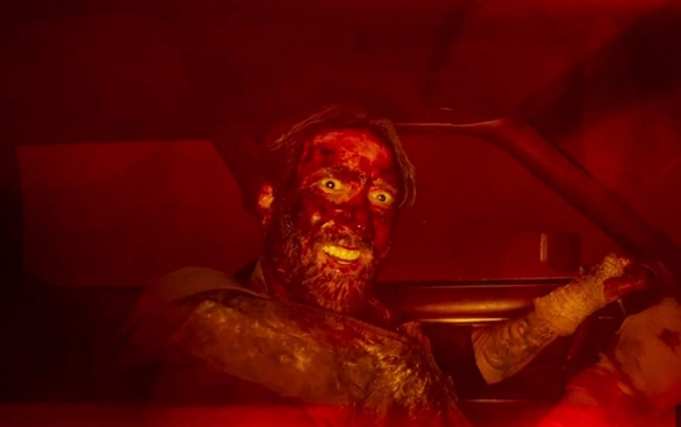 A bloody, crazy-eyed Nicolas Cage drives a car in Mandy