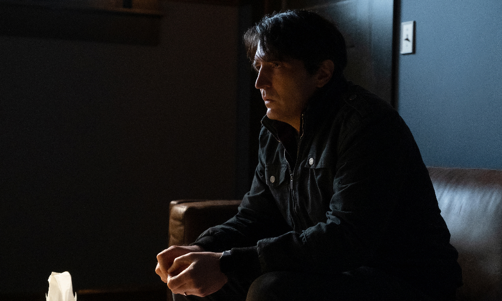A distraught man sitting in a dark room.