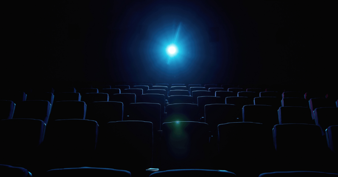 Empty movie theater in darkness with projector light on