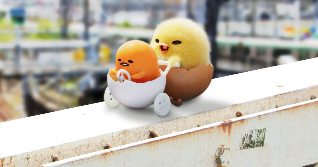 Gudetama, an egg yolk with a face, being pushing in a half-shell stroller by a baby chicken.