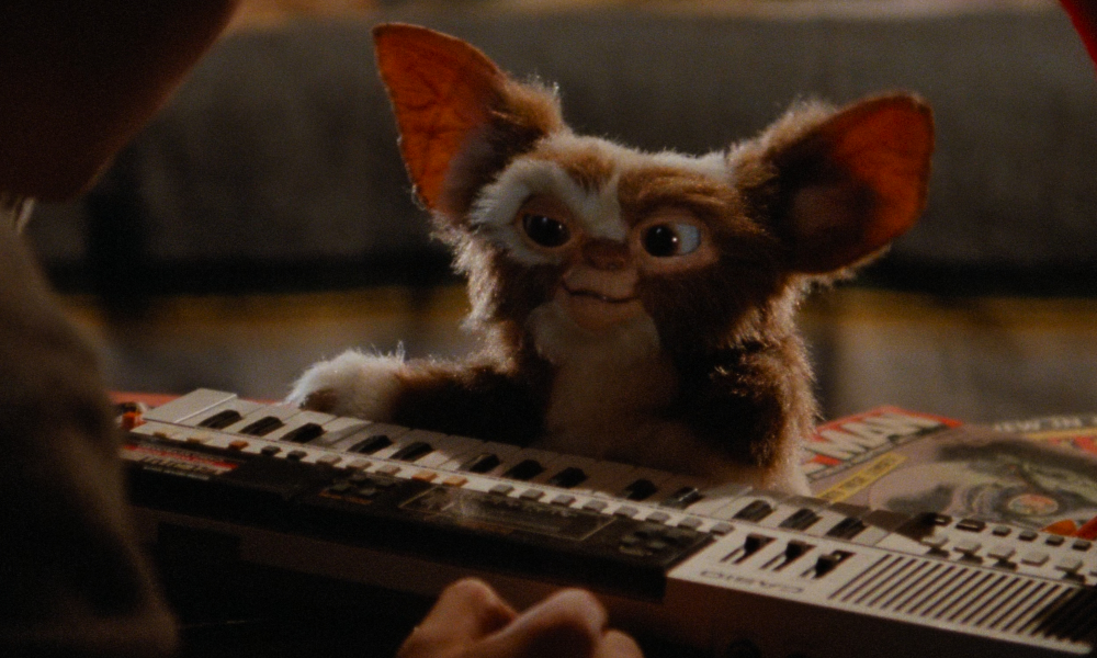 A Gremlin, a furry little creature with big ears, playing the keyboard.