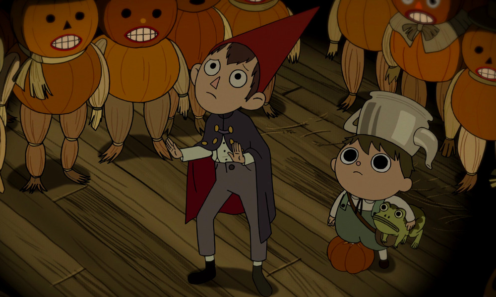 Wirt, a boy wearing a red cone hat, and Greg, a smaller boy wearing a teapot hat, are surrounded by scary pumpkin people.