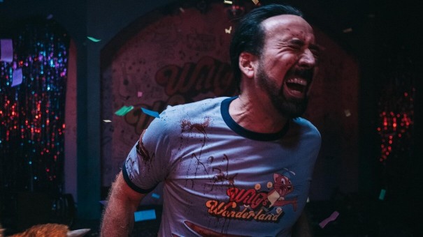 A man wearing a Willy's Wonderland t-shirt winces in pain