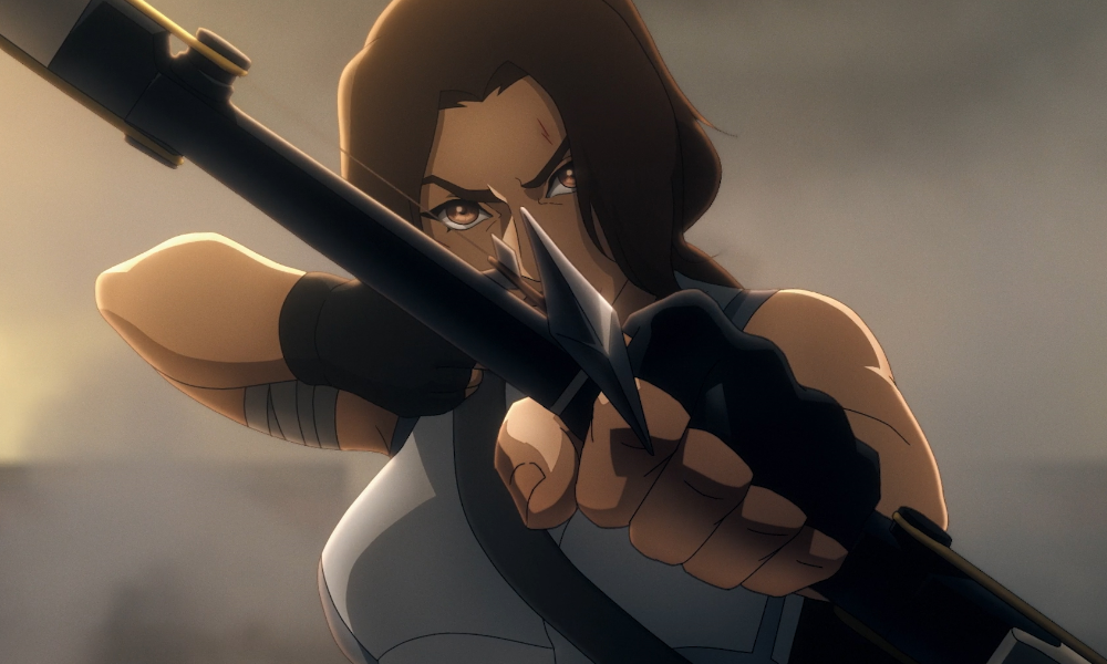 Lara croft, a woman with brown hair and fingerless gloves, points an arrow at the camera.