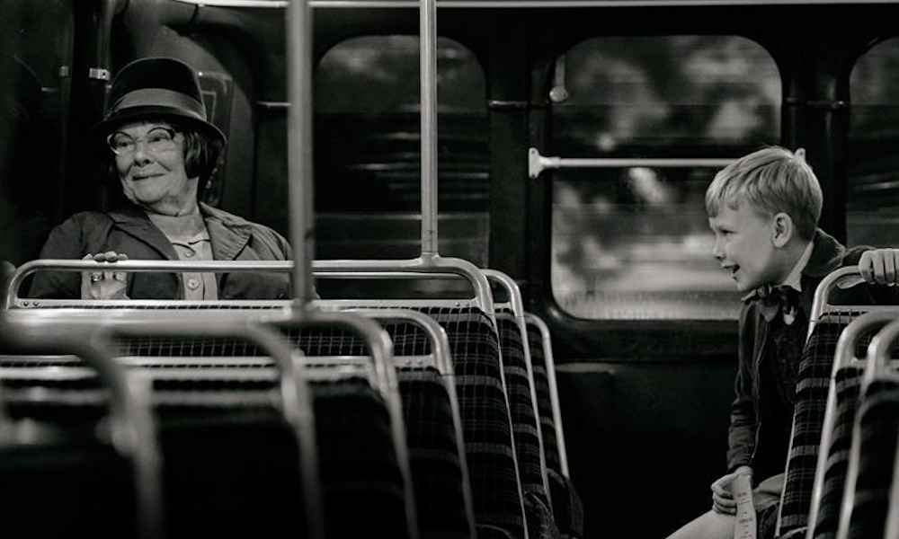 Black and white image of elderly woman and young boy sitting on a bus