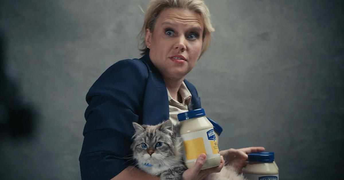 Kate McKinnon holds a cat and several jars of mayonnaise