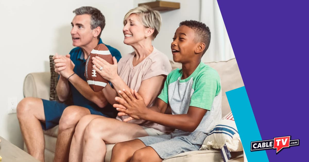 Family sitting on couch cheering for sports