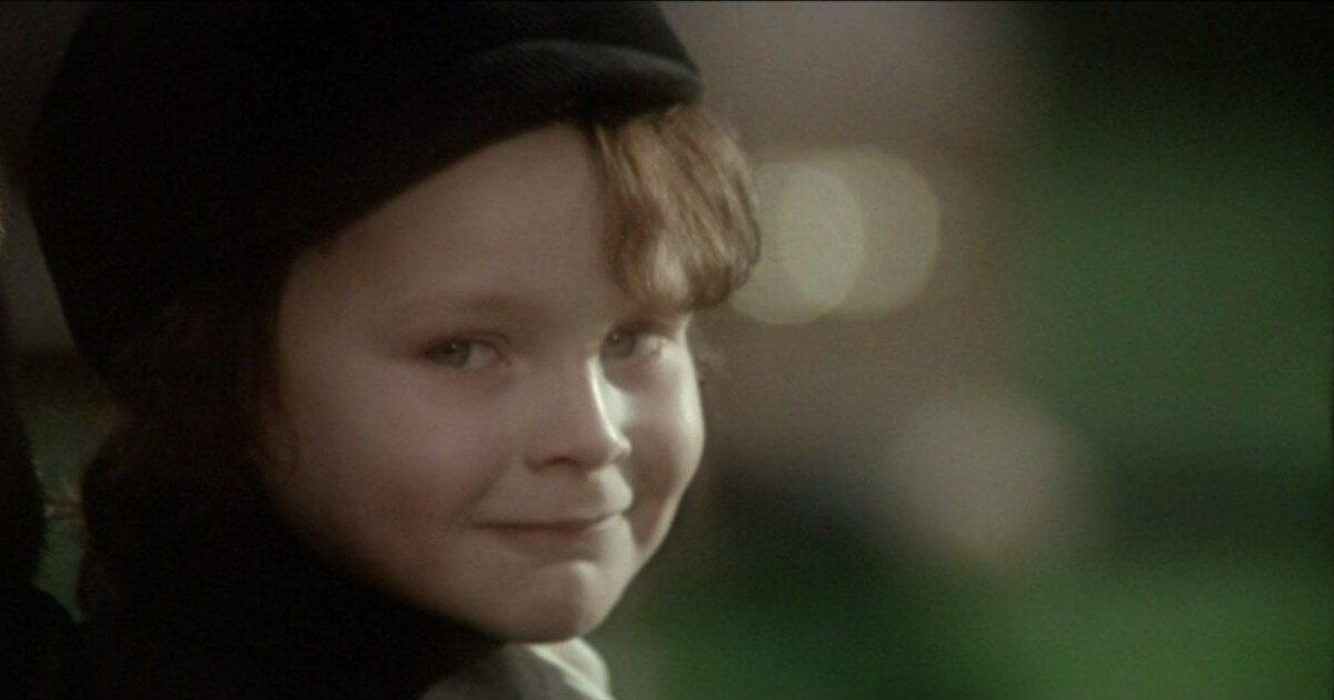 A sweet-looking little boy smiles while looking into the camera.