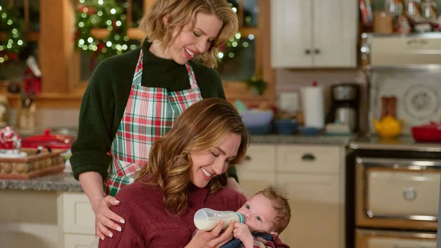 Lifetime and Hallmark Christmas Movies - The Christmas Baby In a scene from the Hallmark Christmas movie The Christmas Baby, two women in a kitchen gaze lovingly at a new baby.