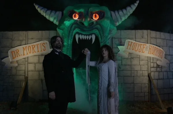 A ghoulish-looking bride and groom appear to welcome visitors to a haunted house.