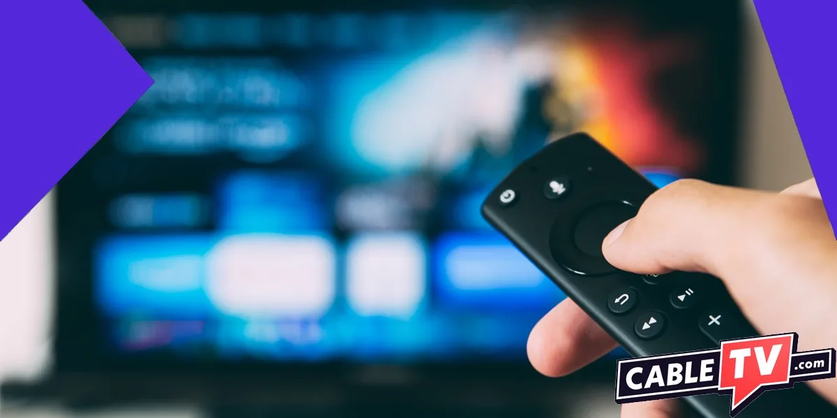 Hand holding streaming remote with blurry tv screen in background