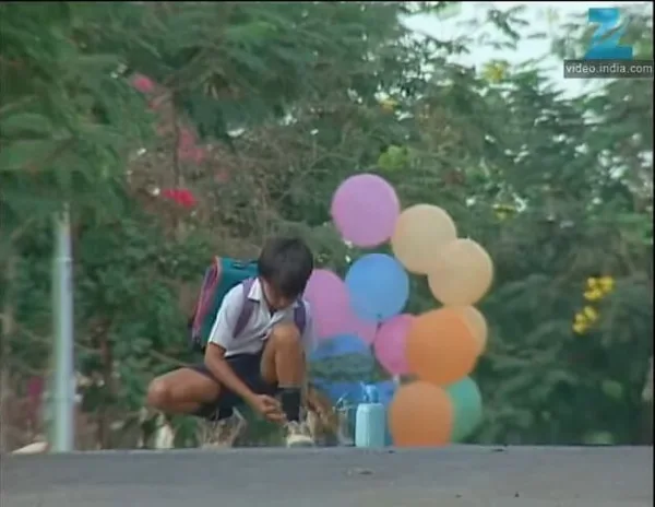 How to Watch Every IT Movie and Show in Order - Woh A young boy kneels to tie his shoes while a bunch of balloons lurks ominously behind him.