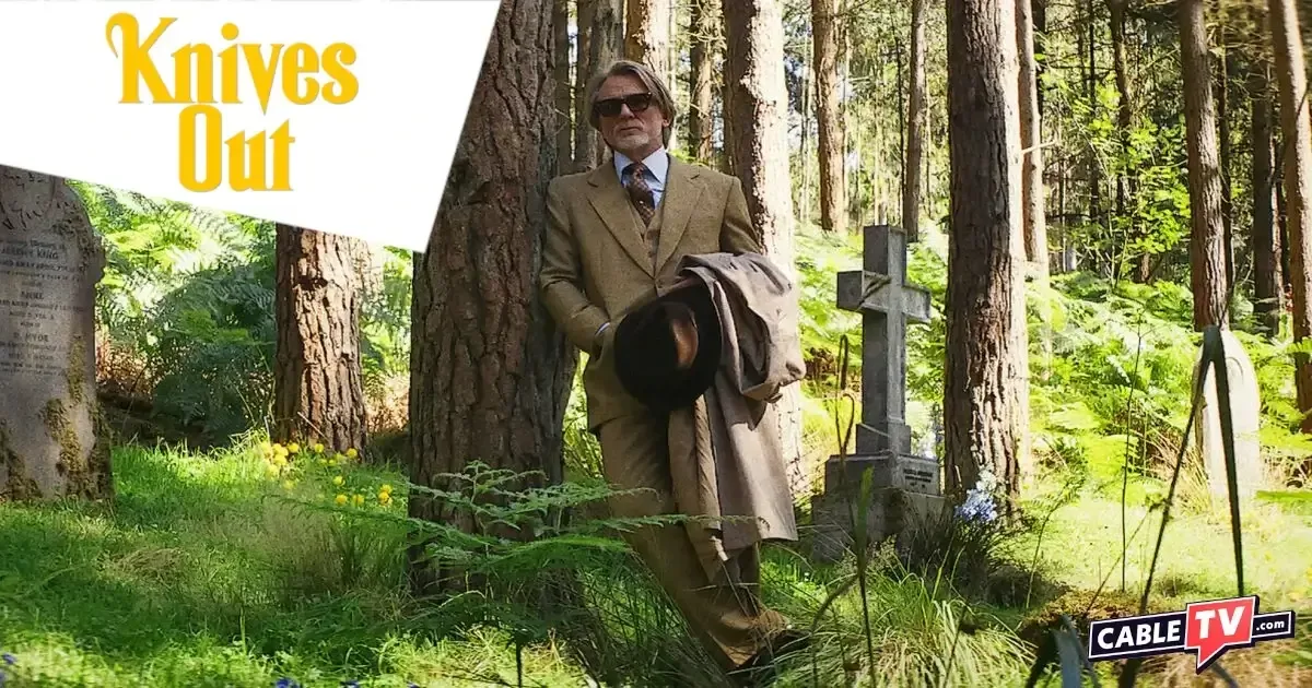 In a scene from Wake Up Dead Man, Benoit Blanc (Daniel Craig) stands in a wooded graveyard.