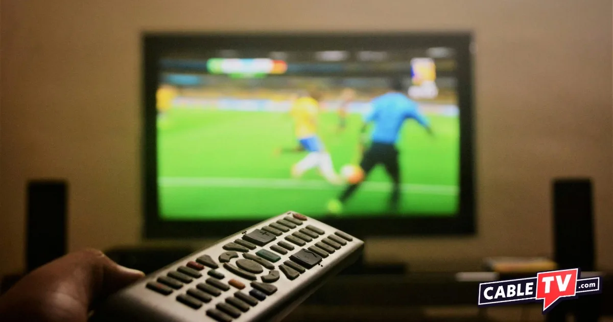 Hand holding a remote control pointed at a tv