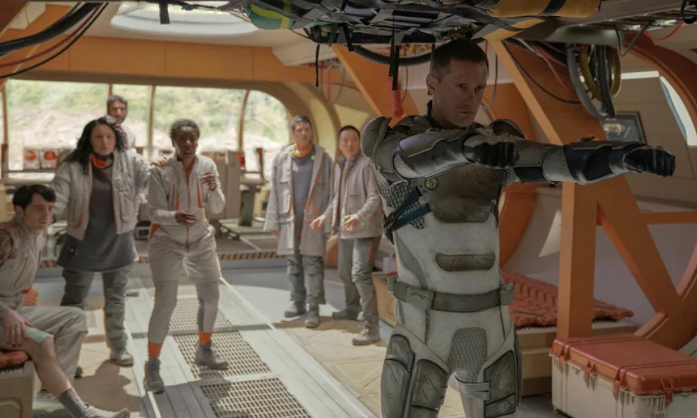 Murderbot1000x600 A humanoid robot aims guns to protect a team of scientists dressed in gray.