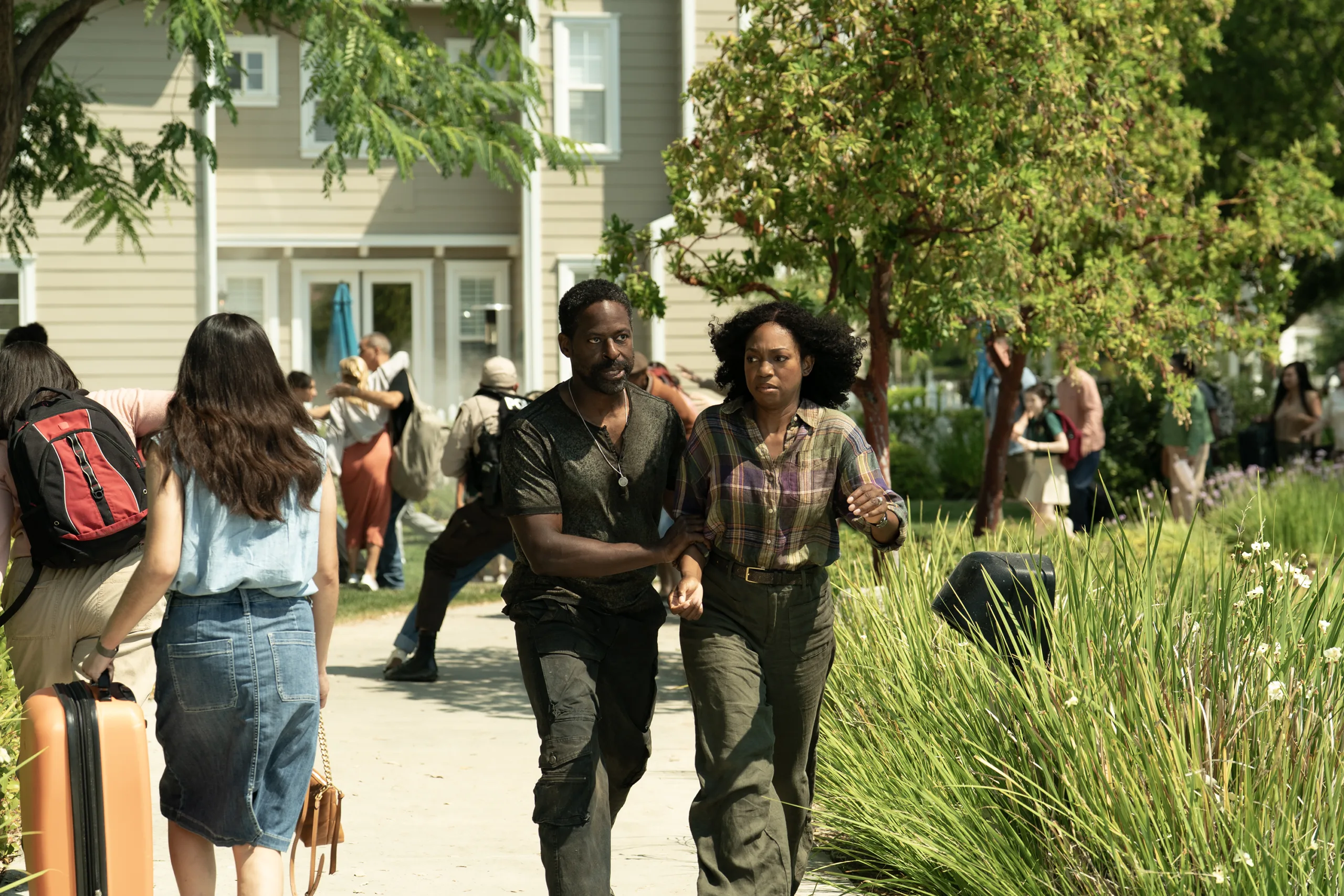 A scene from the TV show paradise with actors sterling k brown and Enuka Okuma running away from a home outdoors