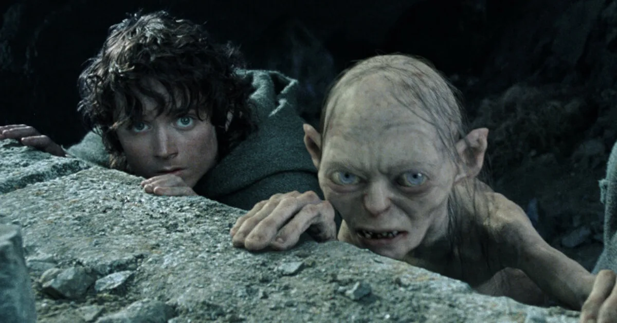 Frodo, a hobbit, and Gollum, an ugly little creature, hide behind a rock.
