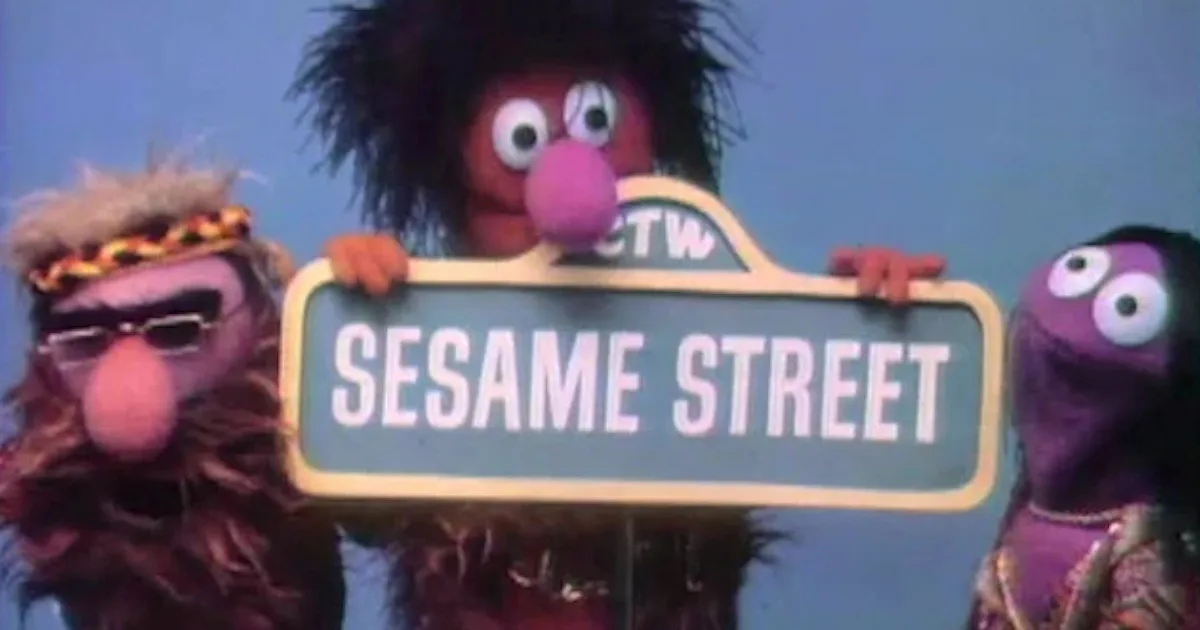Three puppets hold up a "Sesame Street" sign.