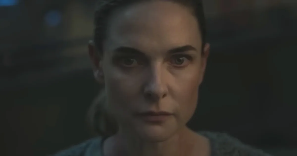 A woman stares down the camera with a serious expression.