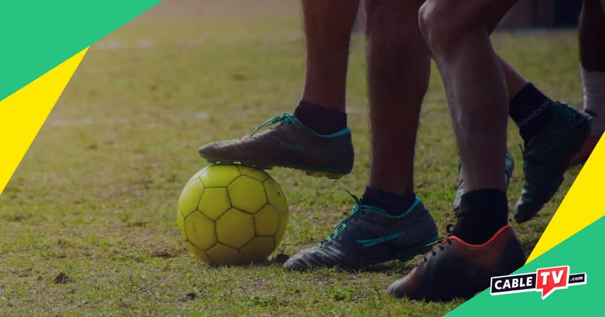 Soccer Hub Page A close-up of soccer players in cleats with one player's foot resting on a ball.