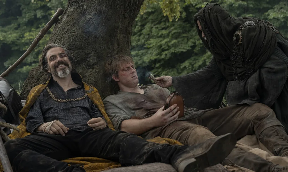 KnightOfTheSeven1000x600 Two injured men rest under a tree; one is smiling, the other frowning.