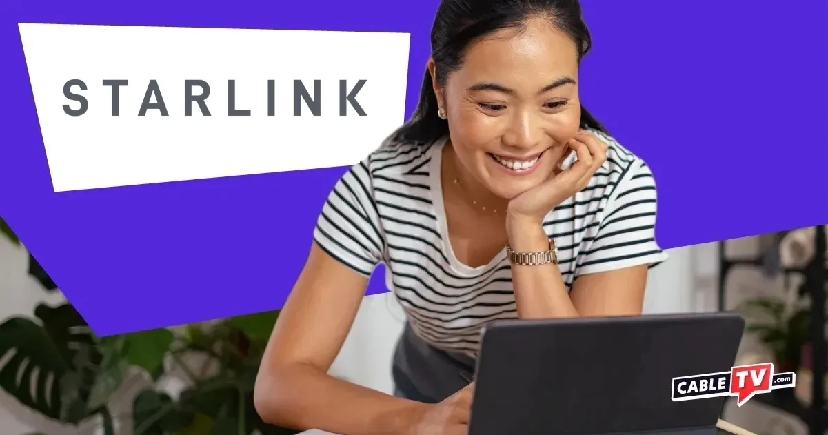 Smiling woman looking at laptop screen with Starlink logo on white field
