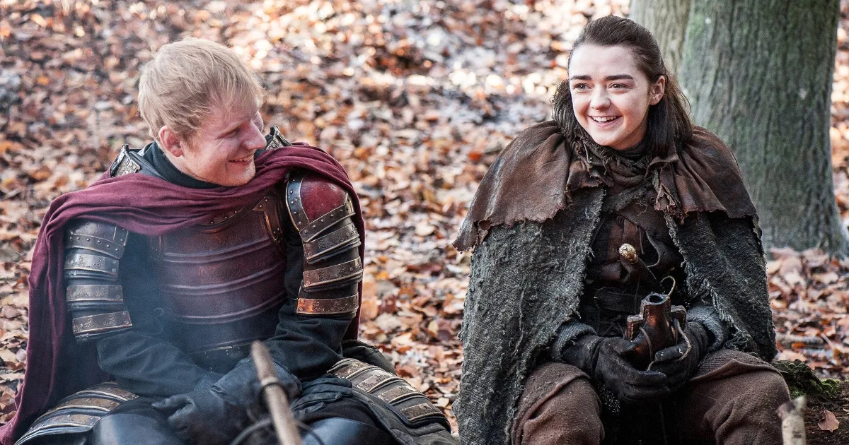 Ed Sheeran, dressed as a knight, sitting next to Maisie Williams as Arya Stark.