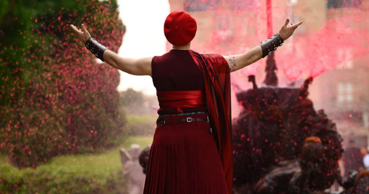 Alan Cumming, from behind, wearing an all-red outfit amid a spray of red confetti on the set of "The Traitors."