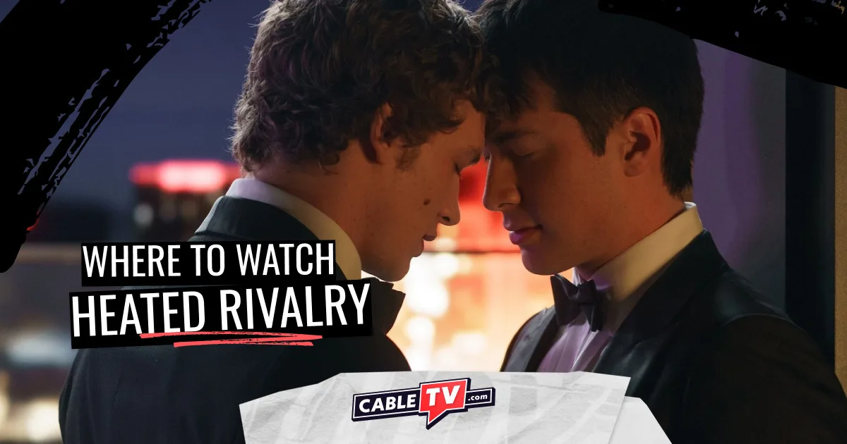 In a dark room, two young men in tuxedos touch foreheads romantically.