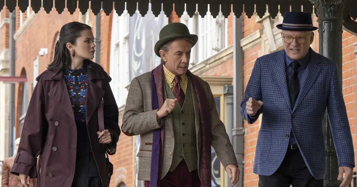 Mabel, Oliver, and Charles walk down the street while discussing something.