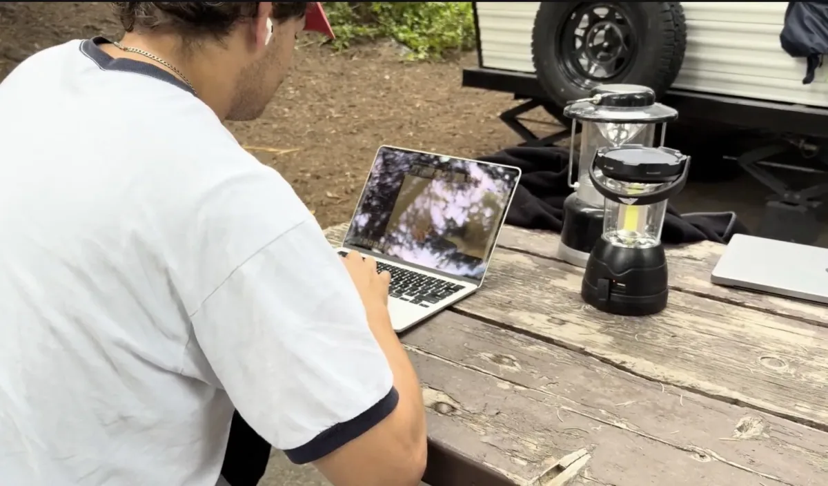 Someone using a laptop outside on a picnic table.
