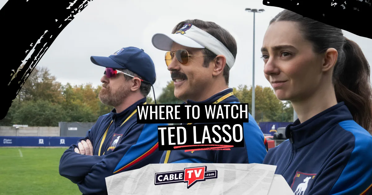 where to watch ted lasso Three soccer coaches stand shoulder-to-shoulder watching the action on the pitch.