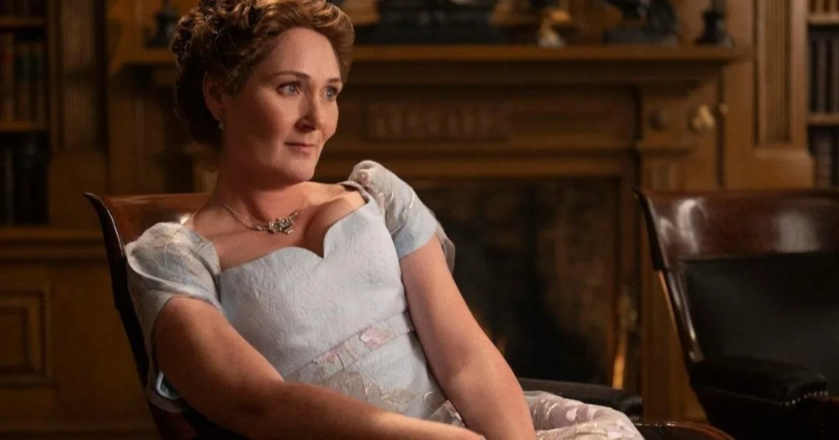 VioletBridgerton1200x630 Violet Bridgerton, a middle-aged woman in a power blue Regency gown, sits calmly.