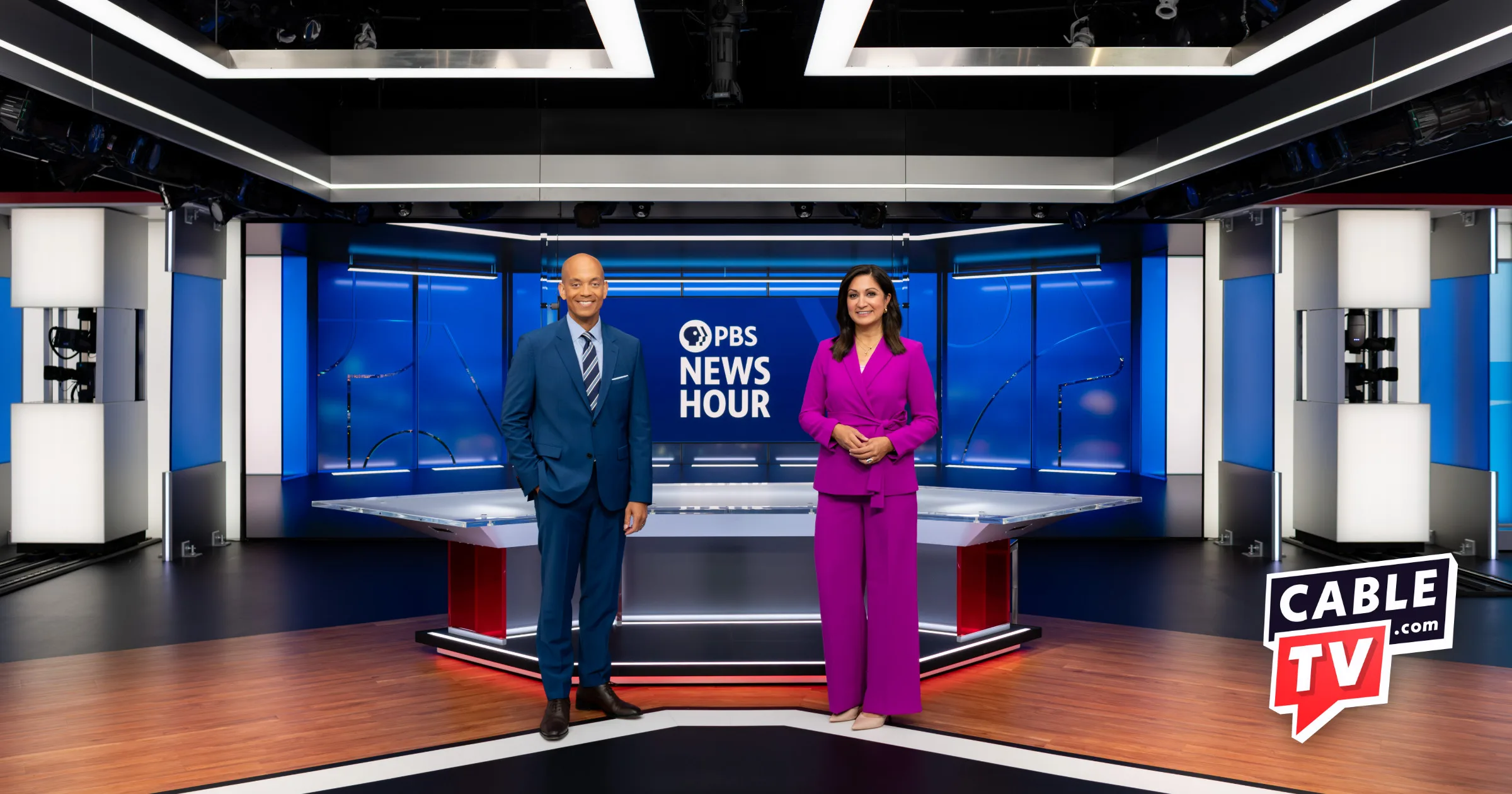 PBS News Hour anchors stand at the front of the set with a CableTV.com logo in the corner.