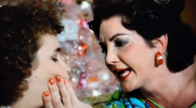 Mrs. Smith (Laura Waterbury) explains Christmas to Monique (Diane Franklin) in a scene from Better Off Dead.mouth