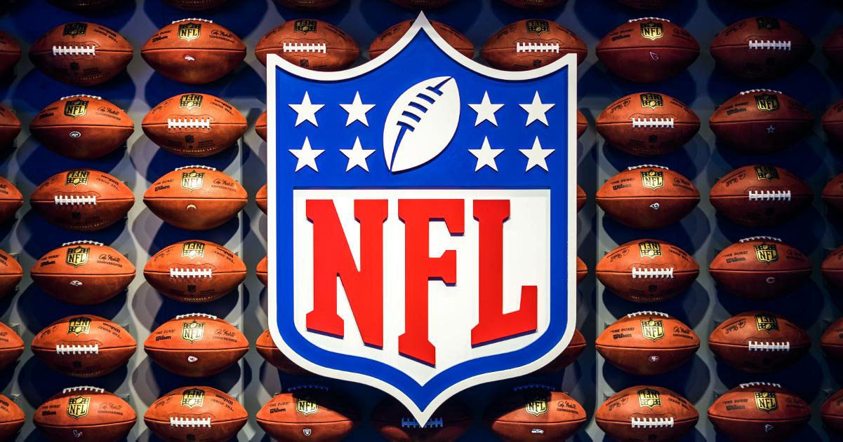 NFL logo in front of rows of footballs.