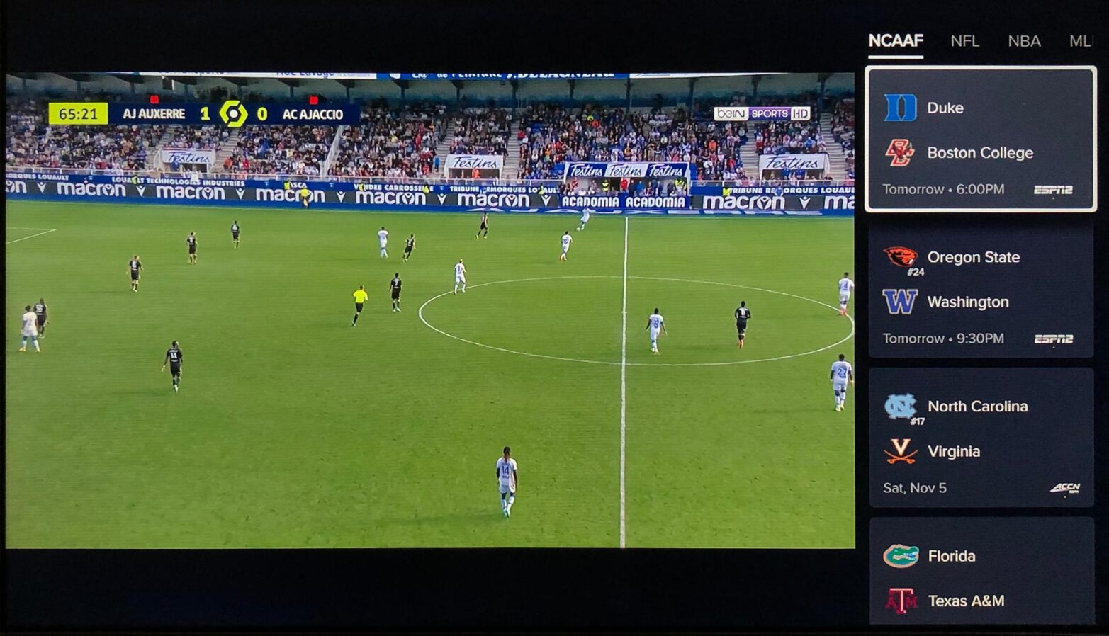 A Ligue 1 soccer match plays while displaying upcoming NCAA football games to the right of the video player.